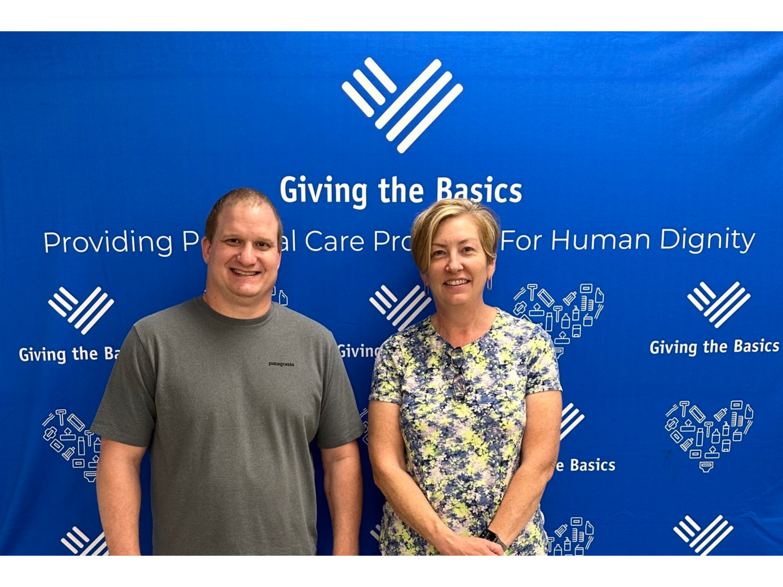 Kevin and Jill in front of the Giving the Basics banner.