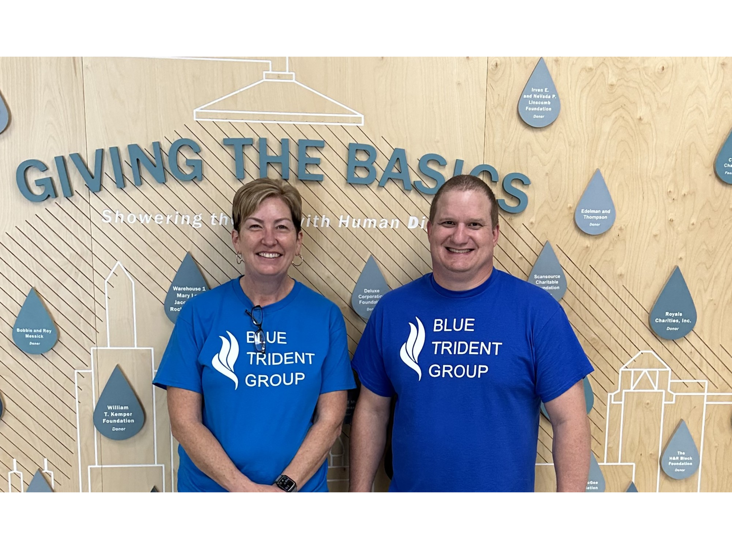 Jill and Kevin in front of the Giving the Basics donor board.